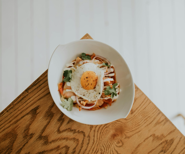 A beautifully plated Korean dish with kimchi and a fried egg on a wooden table, perfect for lunch or dinner.