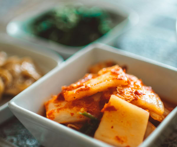 Close-up of spicy Korean kimchi in a ceramic bowl, showcasing traditional flavors and vibrant colors.
