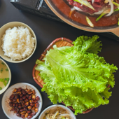 Delicious Korean barbecue set featuring bulgogi and traditional side dishes served with fresh lettuce.