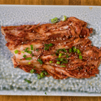 Close-up of fresh homemade kimchi garnished with green onions and sesame seeds on a textured plate.