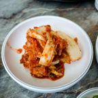 Delicious traditional Korean kimchi served in a white bowl, perfect for Asian cuisine enthusiasts.